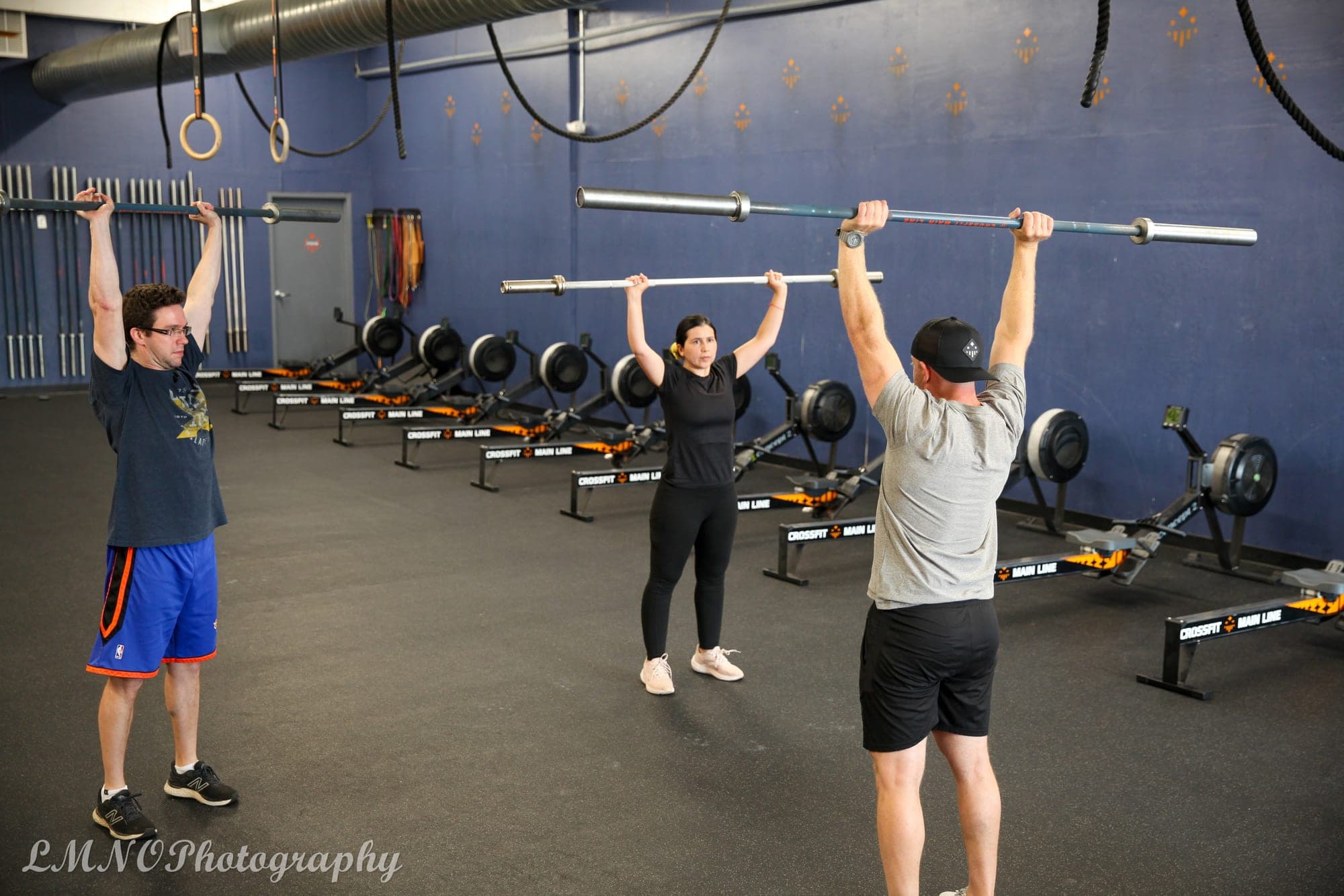 A coach leading members through an overhead press at CrossFit Main Line